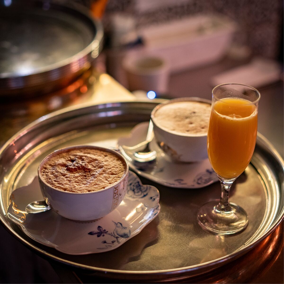 Zwei Tassen Cappuccino und ein Glas Orangensaft auf einem Tablett im Café Wunderkammer