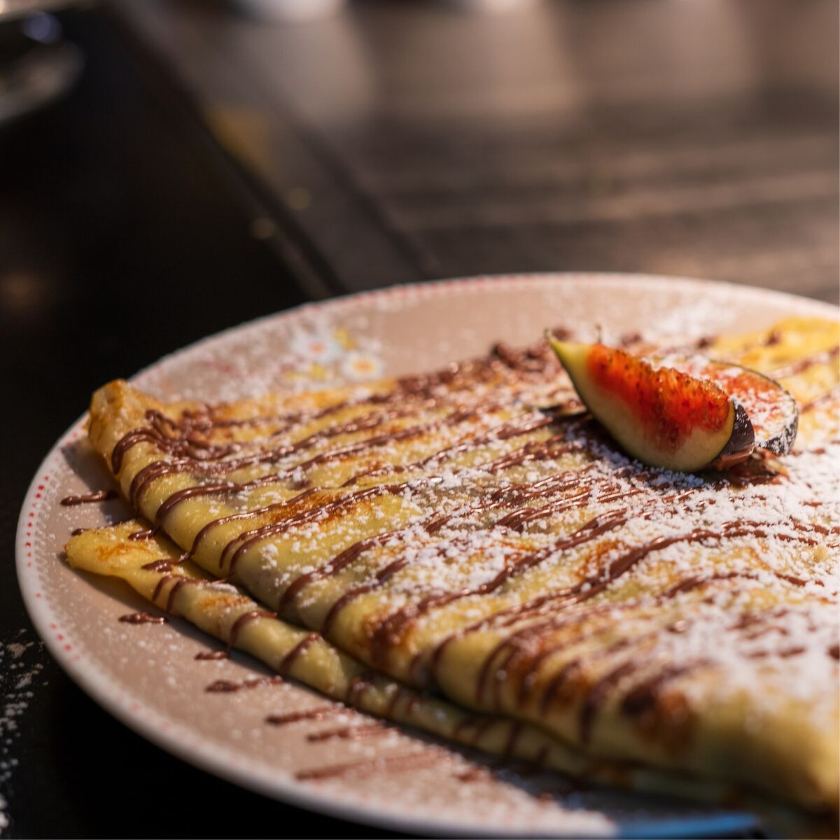 Süßer Crêpe mit Schokosauce, Puderzucker und frischer Feige im Café Wunderkammer