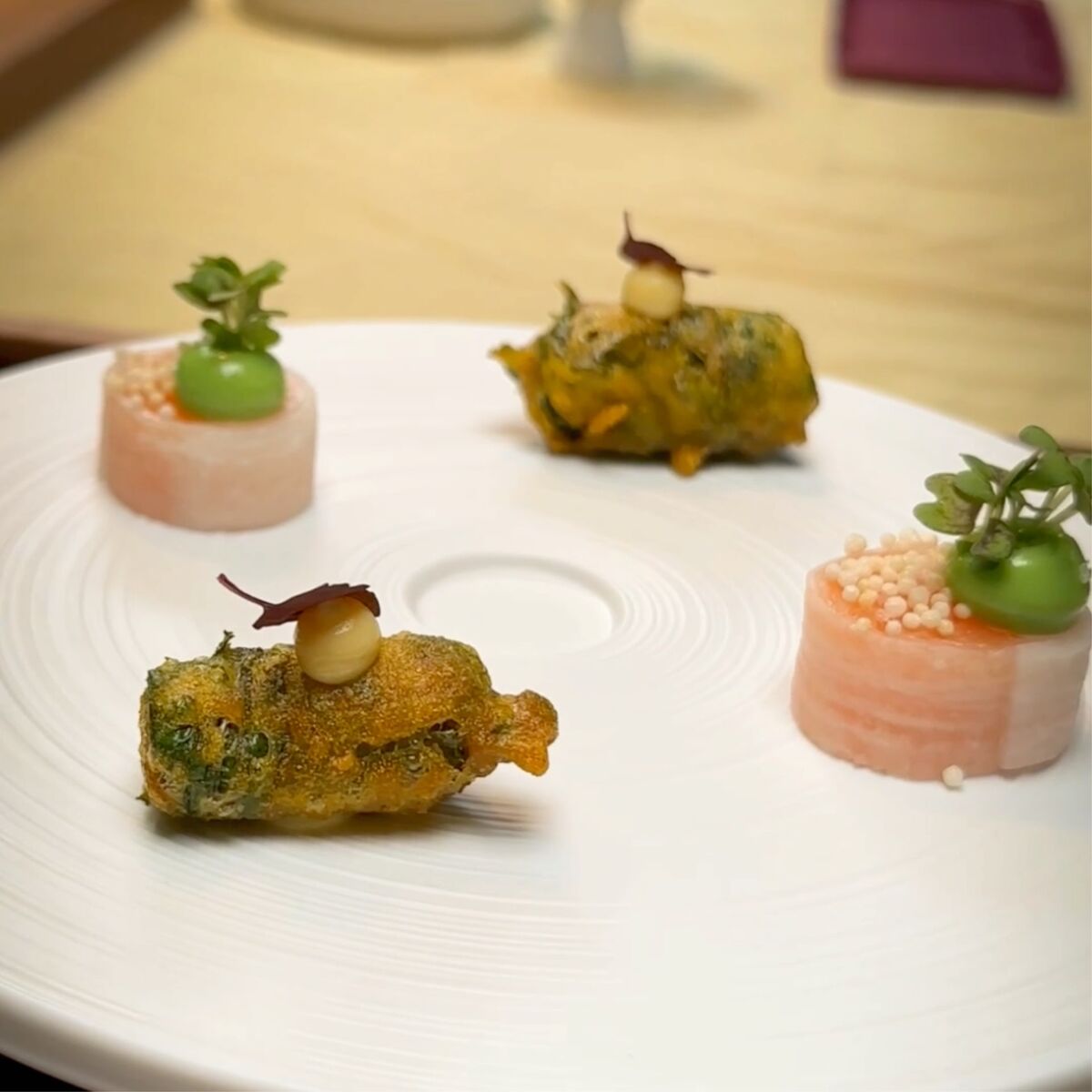 Fein angerichtete Vorspeise mit frittiertem Gemüse und feinen Toppings auf weißem Porzellanteller