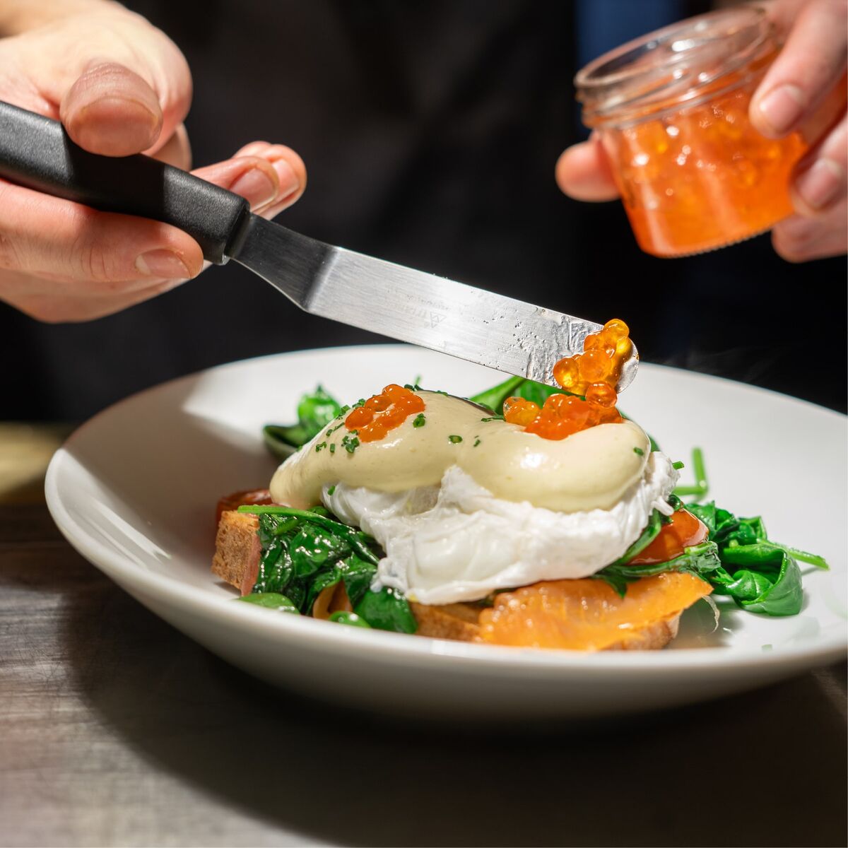 Eggs Benedict mit pochiertem Ei, Lachs, Spinat und Kaviar auf Brot im Café Wunderkammer