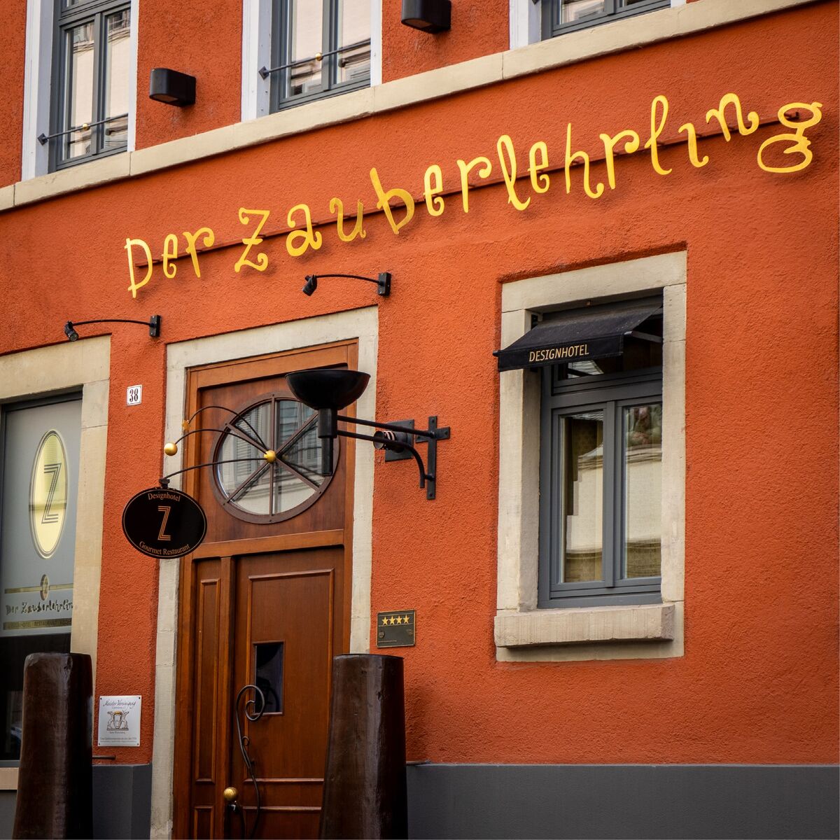 Fassade des Sterne-Restaurants Der Zauberlehrling in Stuttgart mit hölzerner Eingangstür und goldener Schrift