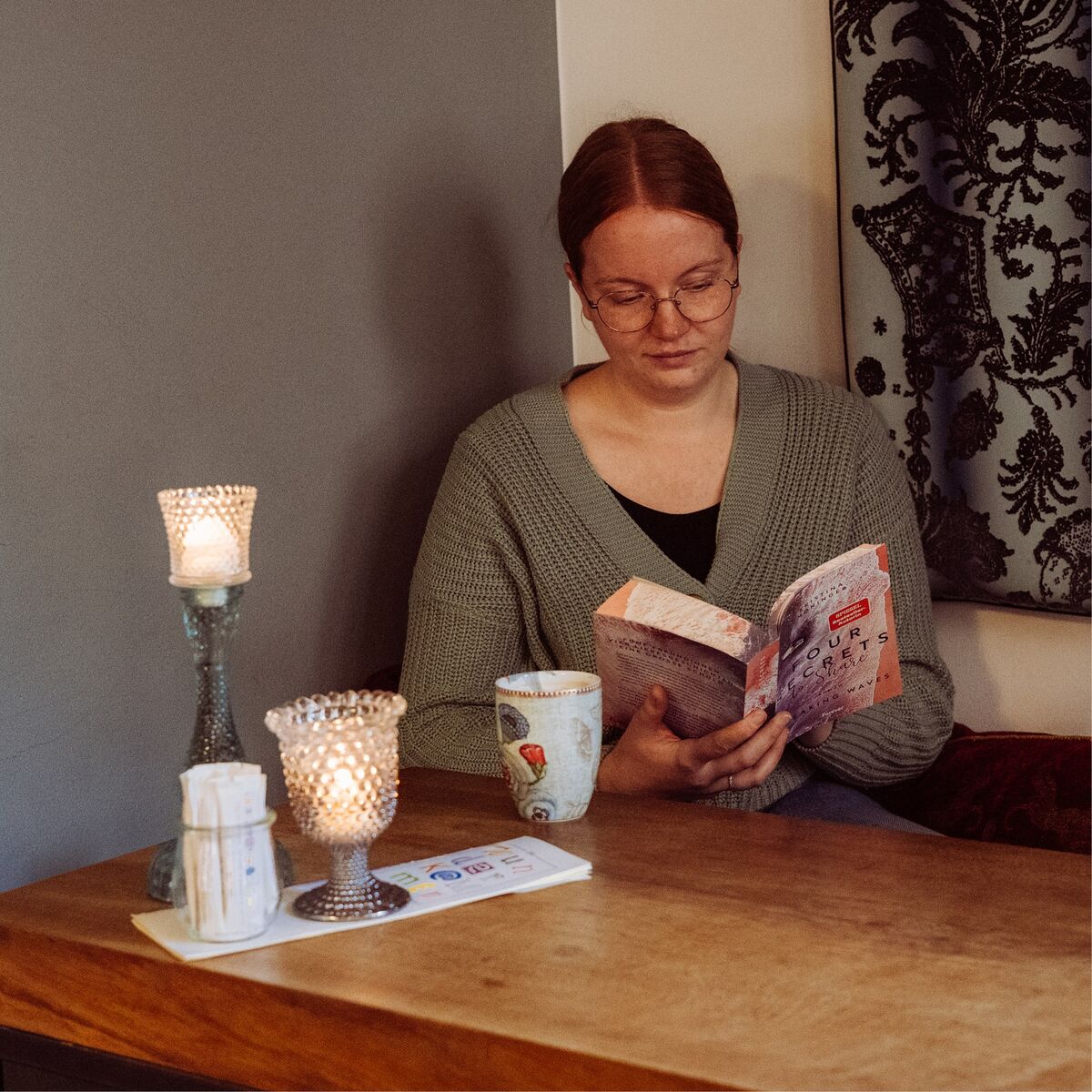 Frau liest entspannt ein Buch bei Kerzenschein im Café Wunderkammer